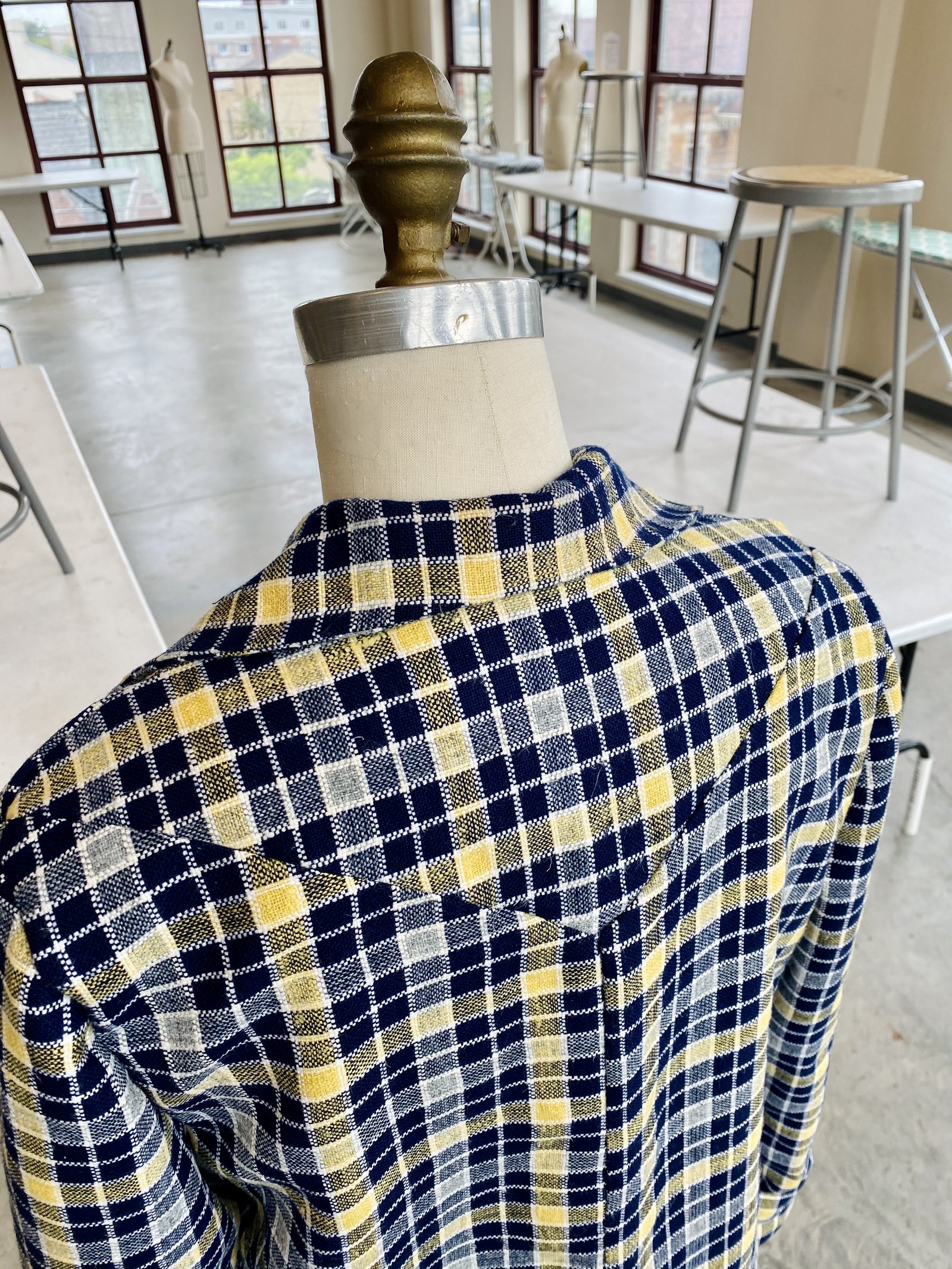 Back yoke detail of a navy and yellow plaid trench coat